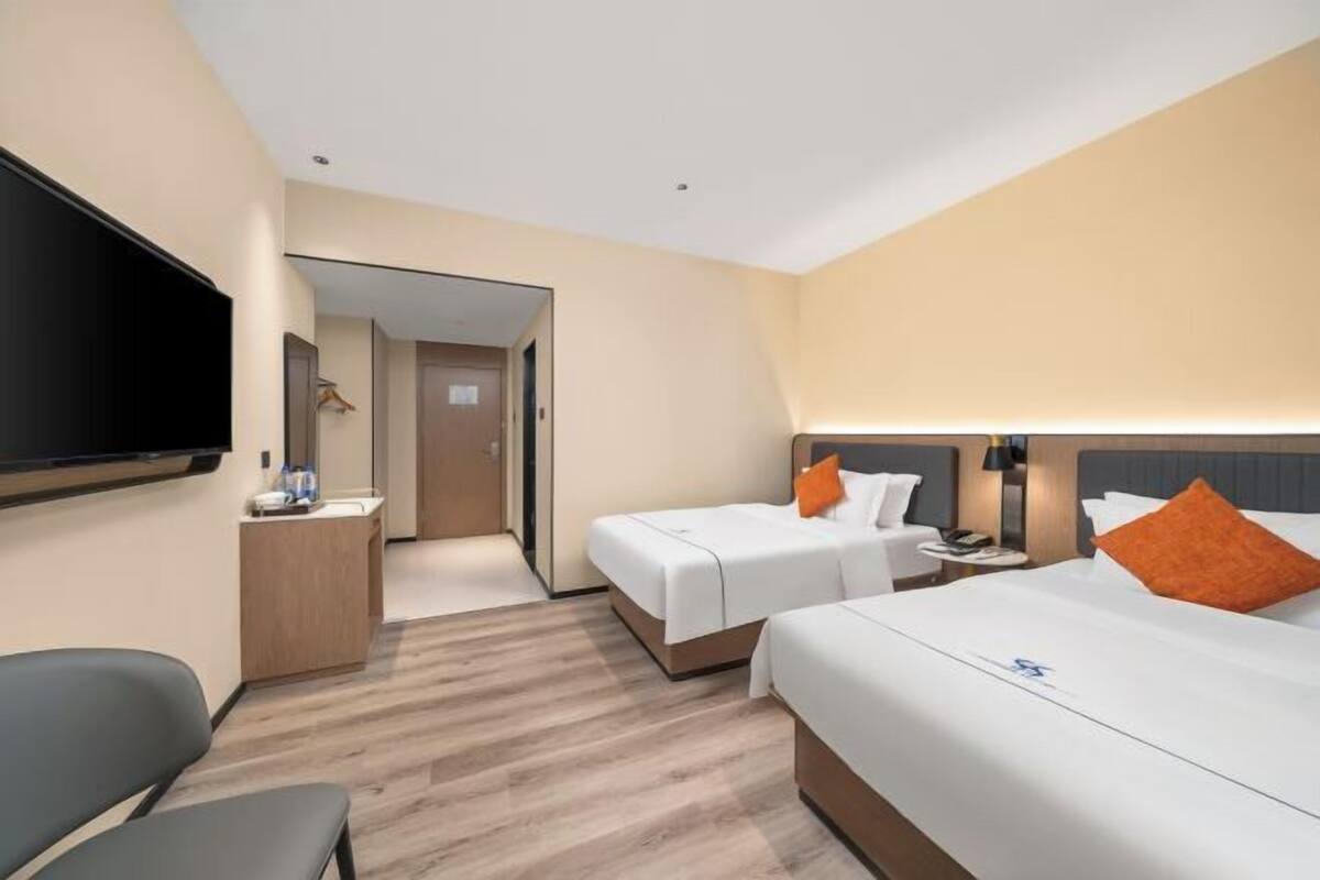 Habitació d'hotel amb dos llits, televisió, escriptori i una cadira.