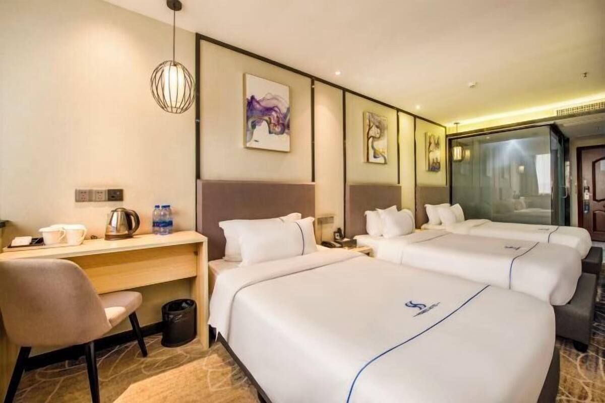 Habitació d'hotel amb dos llits, una taula, una cadira i un safataire.