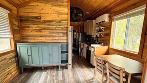 Une cuisine de taille réduite, dotée de meubles en bois, d’une table à manger et d’un ventilateur de plafond.