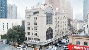 A hotel with a large arched window, multiple floors, and parked cars in front. - Jiahao Hotel (Changzhou)