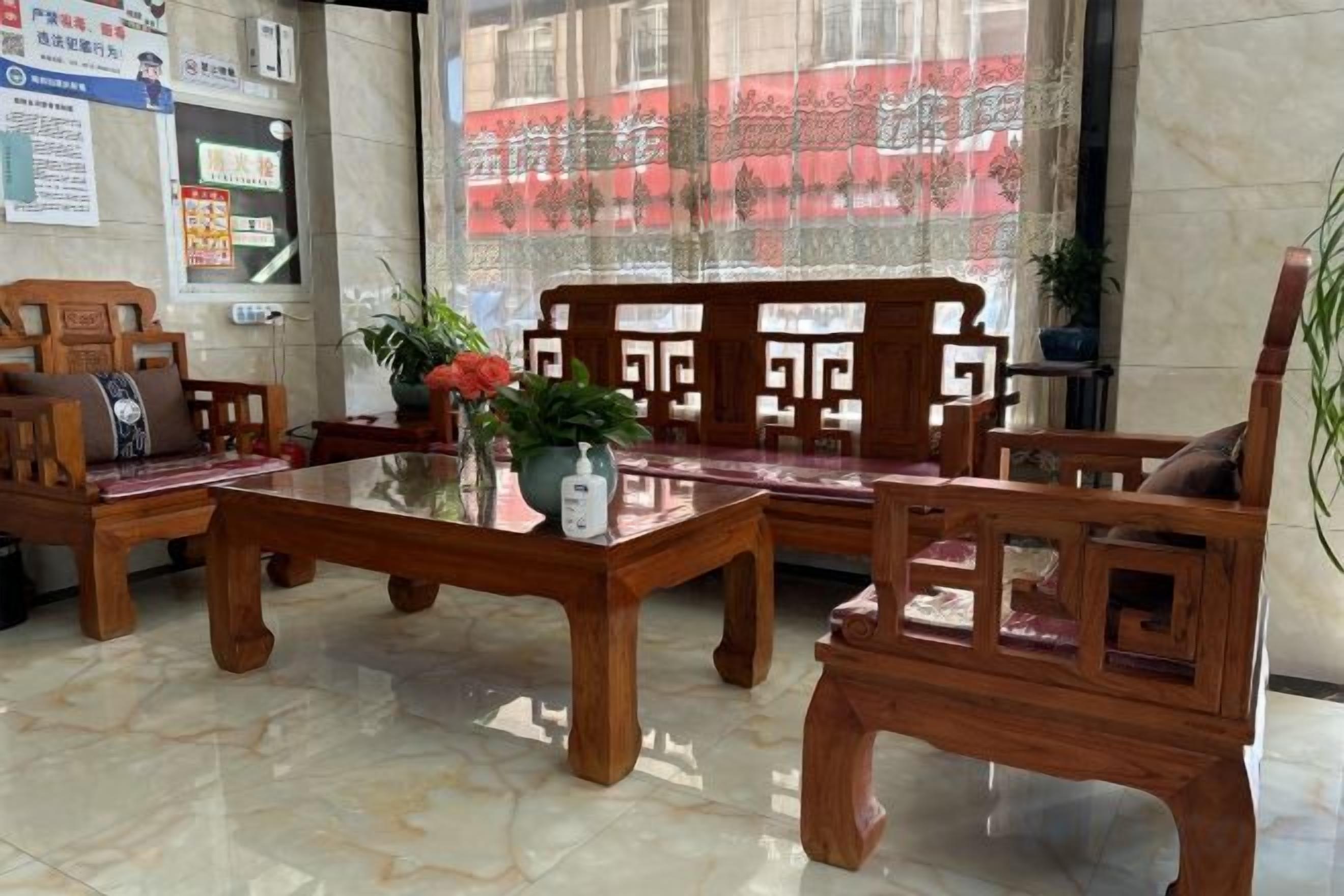 Una zona de recepción de madera con una mesa de vidrio, asientos acolchados y una planta en maceta.