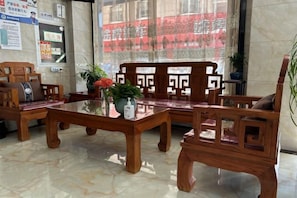 A wooden reception area with a glass-top table, cushioned seating, and a potted plant. - Jiahao Hotel (Changzhou)