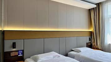 Habitación de hotel con dos camas, cabecera con iluminación integrada, mesita de noche con lámpara y ventana con cortinas.