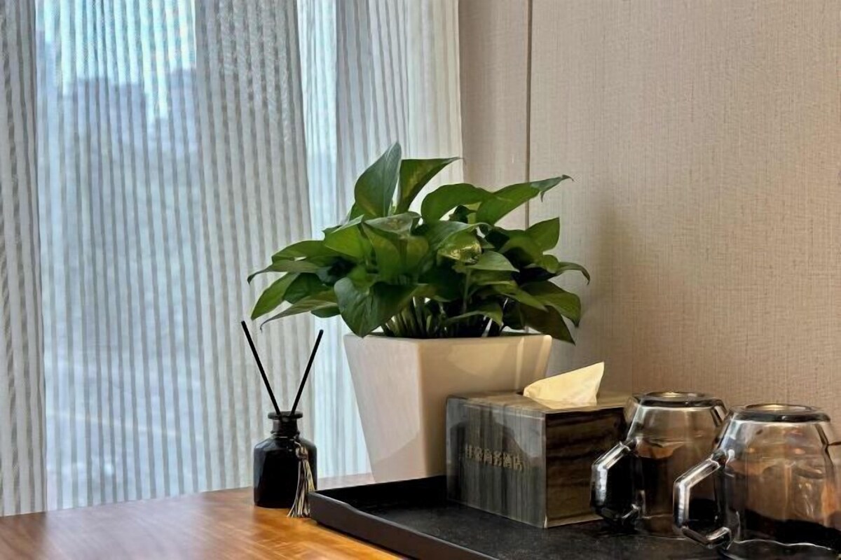 Taula de fusta amb una planta en test, un suport de espelma i dues tasses de vidre.