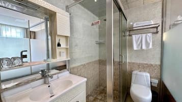 Un baño con cabina de ducha de vidrio, un lavabo blanco y un inodoro.