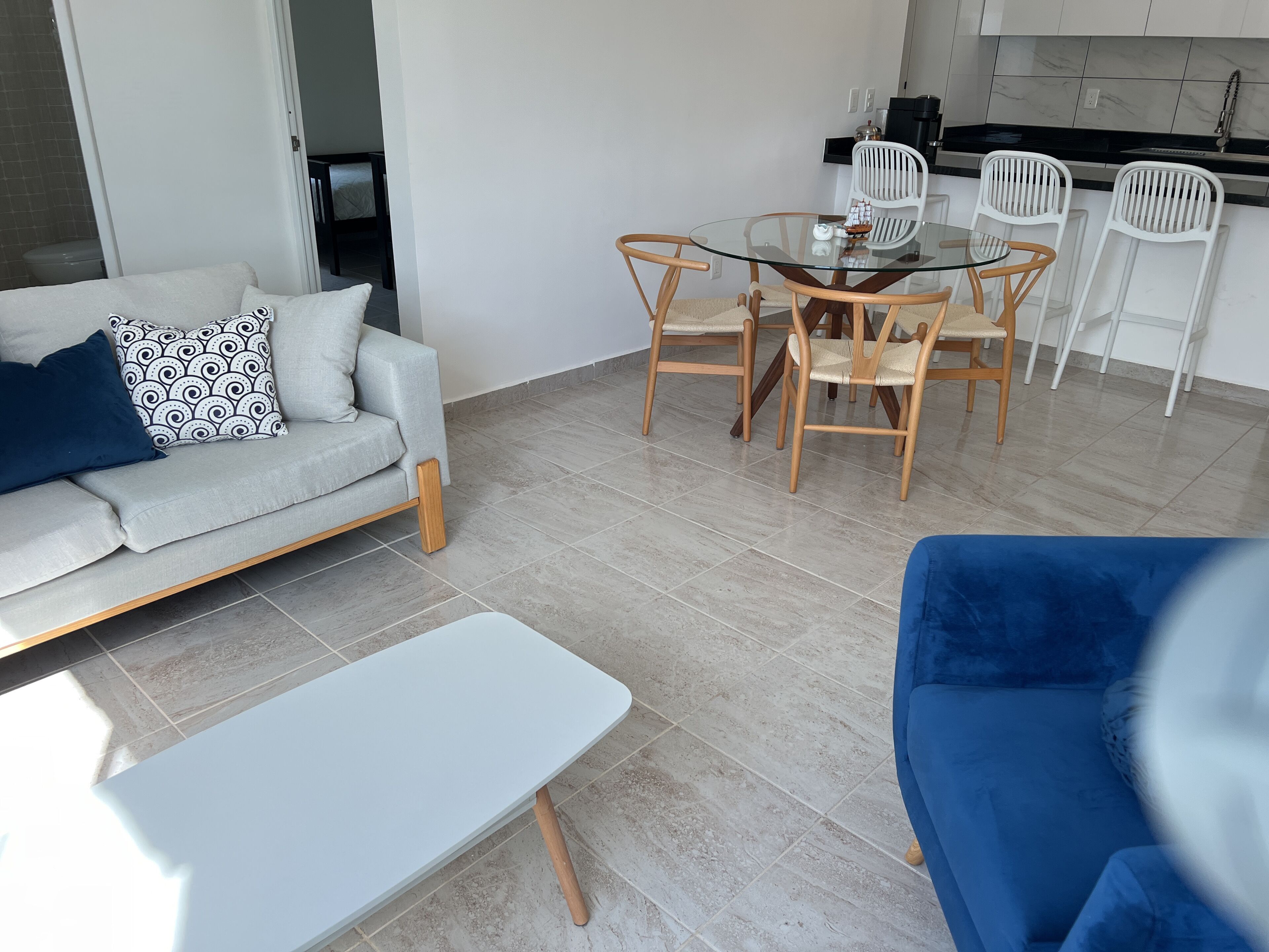 Ein modernes Wohnzimmer mit Sofa, Couchtisch und Essbereich mit Stühlen und einem Glastisch.