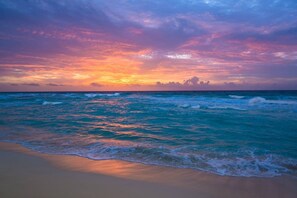 Una playa con olas y un atardecer.