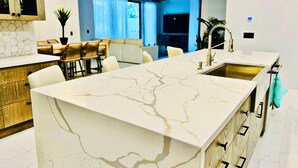 A modern kitchen with a marble countertop, wooden cabinets, and a built-in sink.