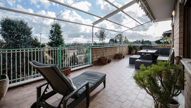 Un espacio al aire libre cubierto con patio, mobiliario y plantas en macetas.