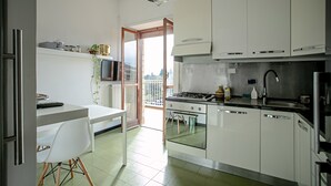 Una cocina moderna con armarios blancos, estufa a gas y comedor con mesa y sillas blancas.