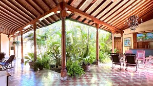 A covered outdoor area with a checkered floor, wooden pillars, and ceiling fans. - Hotel Colonial Victonella (Granada)