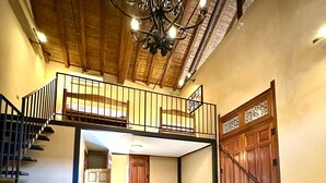 A room with a loft bed, a desk with a laptop, and a staircase leading to an upper level. - Hotel Colonial Victonella (Granada)