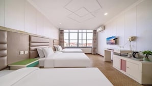 Habitación de hotel con dos camas, un escritorio, un televisor y una ventana con vistas.