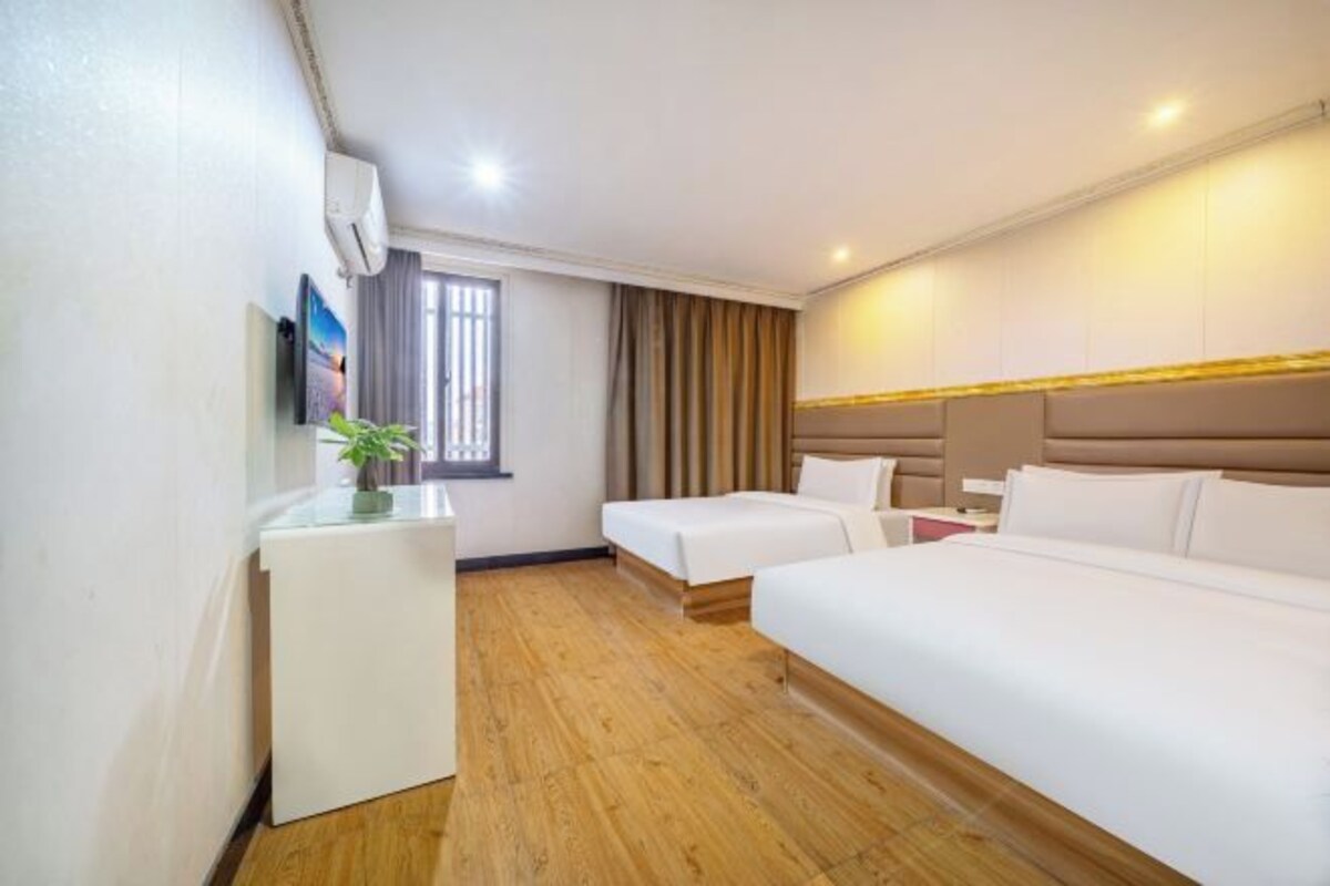 A hotel room with a bed, a desk, a chair, a TV, and a window with curtains.