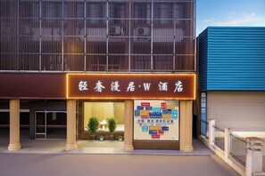 A hotel with a modern facade, illuminated signage, and a visible entrance. - Yue'er Business Hotel (Shanghai)