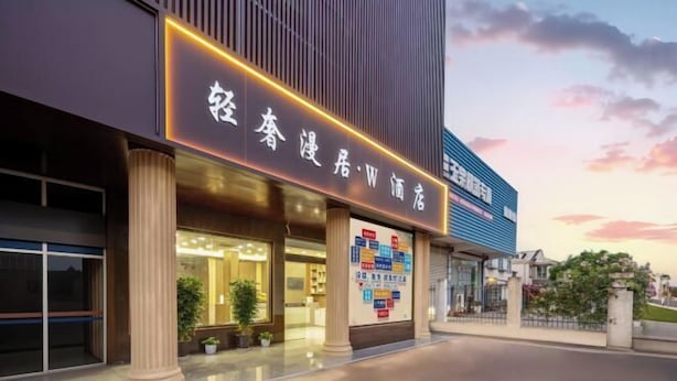 Un hotel con fachada moderna, amplias columnas y un cartel llamativo con caracteres chinos.