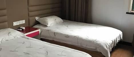 A hotel room with two single beds, a wooden headboard, a red nightstand, and a window with curtains.