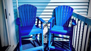 Two blue Adirondack chairs on a porch with a blue and white striped exterior wall. - Family-friendly, Updated Condo- Stocked Beach Closet-Steps to Crescent Beach-NMB (North Myrtle Beach)