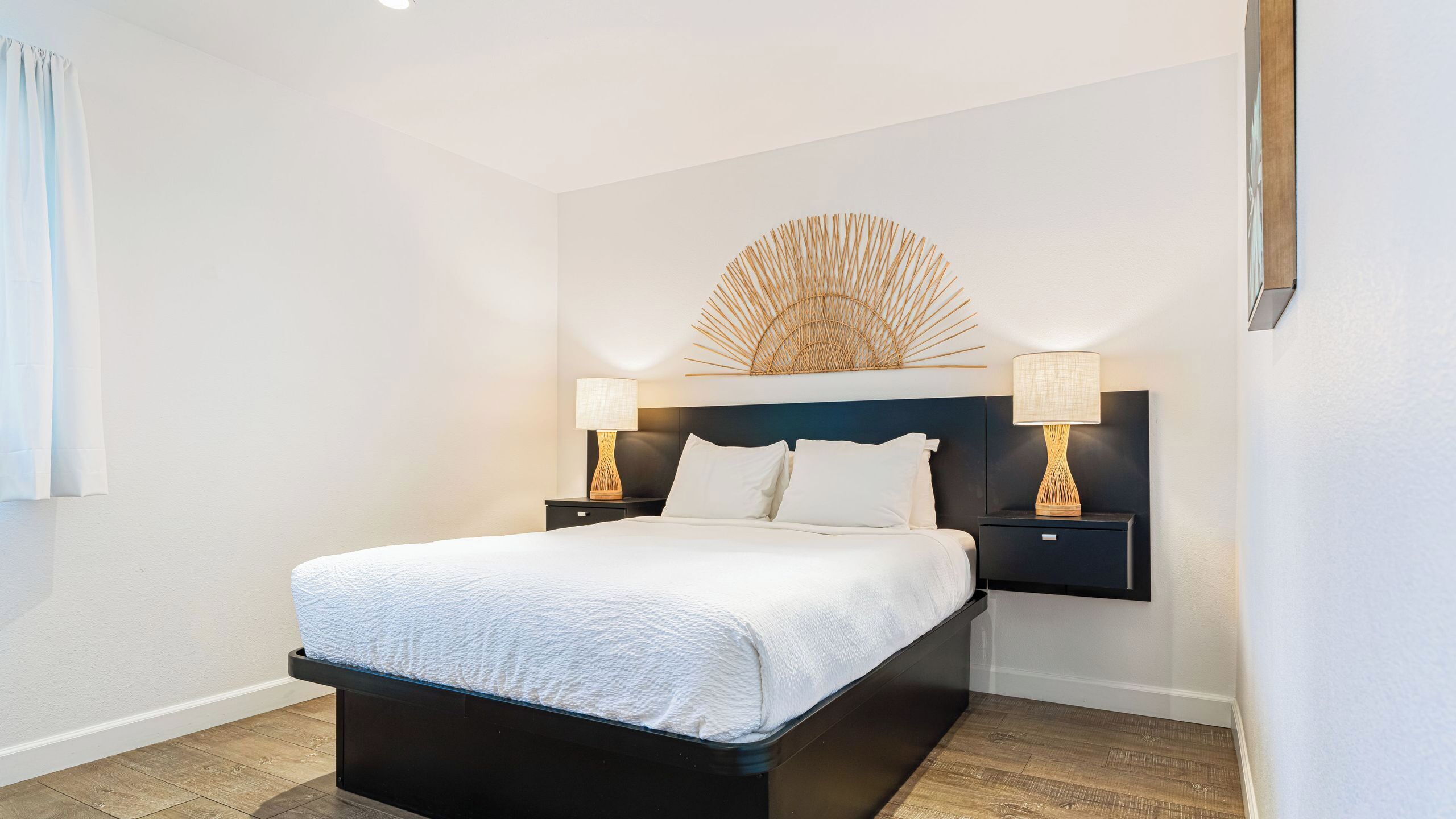 Habitación de hotel con cama, dos mesitas de noche, una lámpara de pared y un adorno mural.