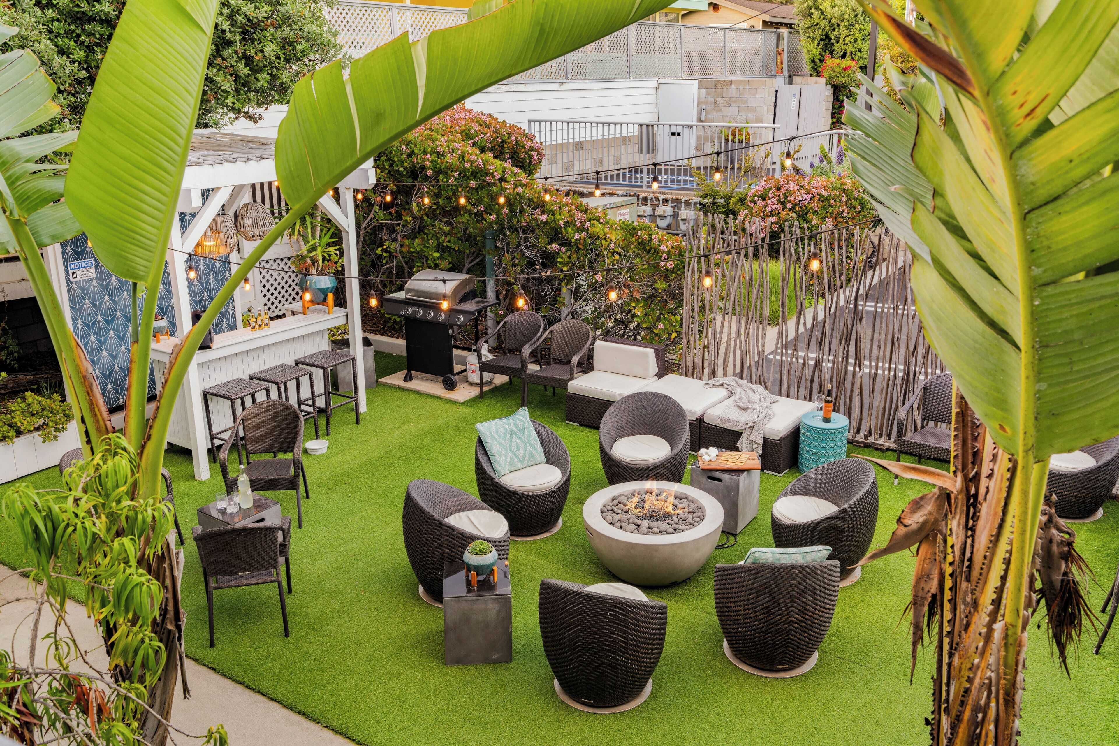 An outdoor patio with wicker furniture, a fire pit, and string lights.