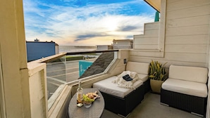 A balcony with a view of the sea, a sofa, a small table with food, and a potted plant. - 2 Cayucan Bungalows Steps to Beach + Shared Lounge Sleeps 12 (Cayucos)