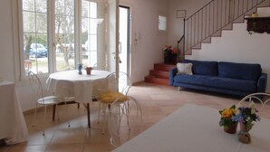 Un salon avec un canapé bleu, une table à manger avec des chaises et un escalier.