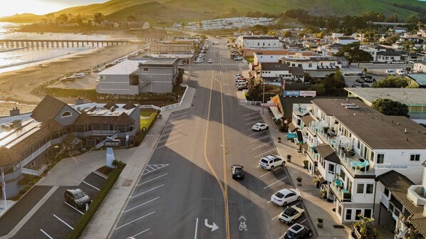 A coastal town with a beach, a pier, and a street lined with houses and shops.