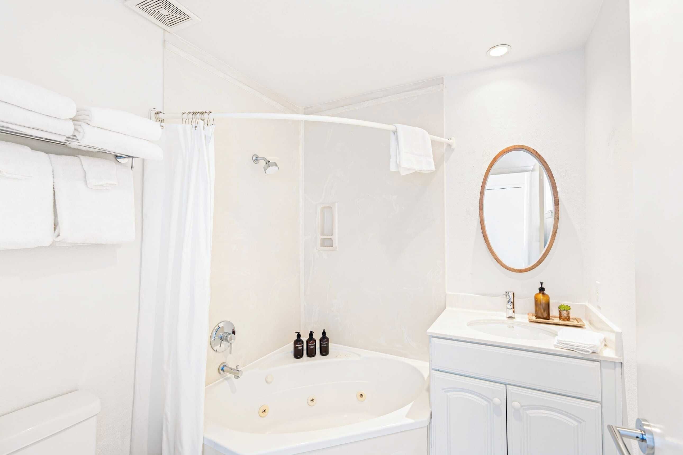Un baño moderno con bañera, ducha, tocador con espejo y toallas ordenadas.
