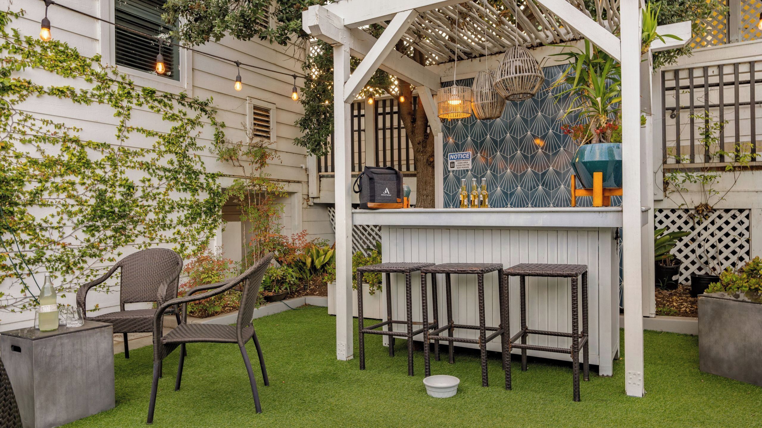 Un patio con mobiliario de mimbre, una barra y un colgante decorativo.