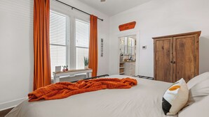 Un dormitorio con cama, un armario de madera, una ventana con persianas y un ventilador de techo.