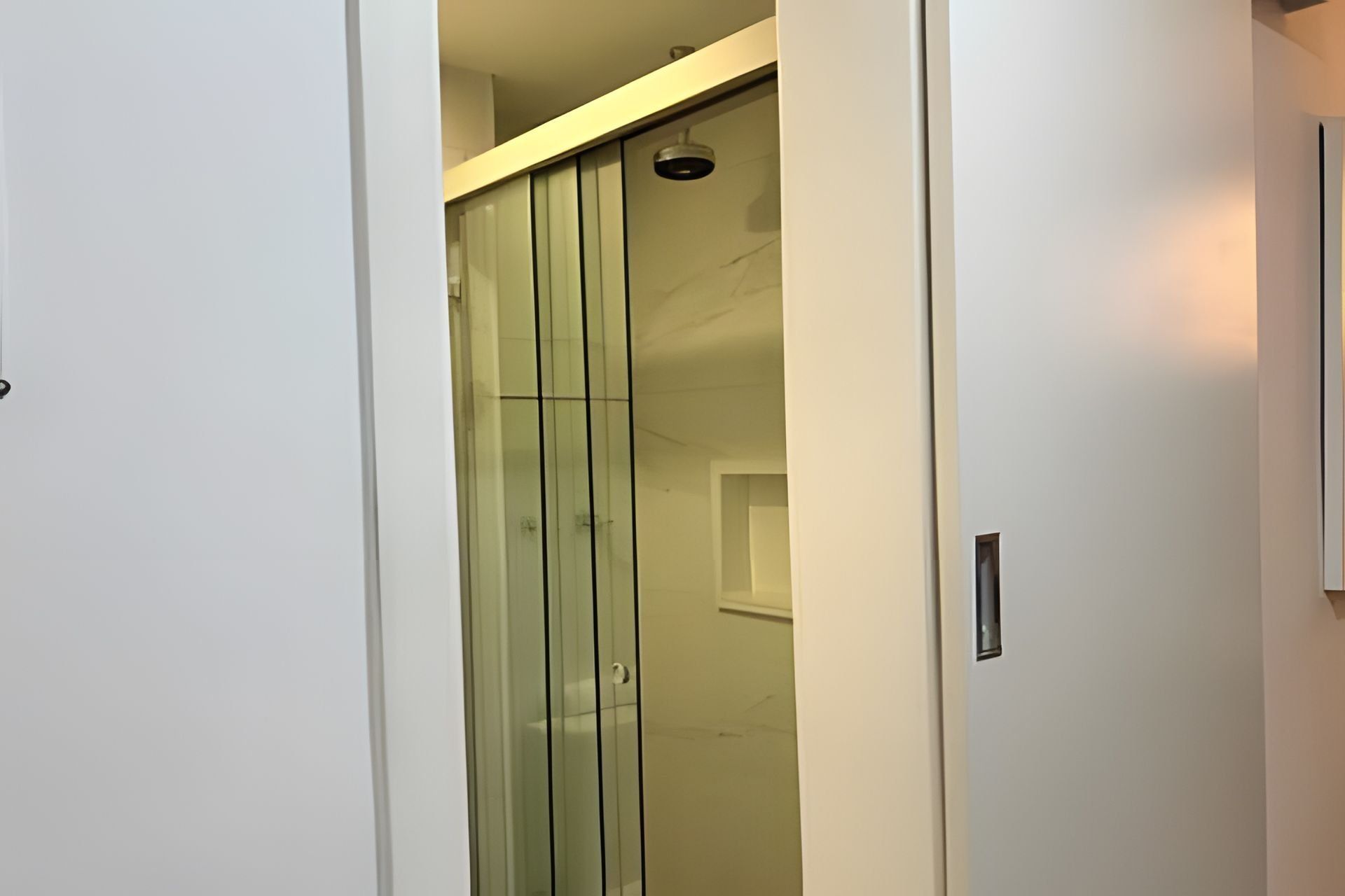 A modern interior with a glass partition, a ceiling light, and a door handle.