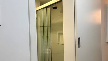 A modern interior with a glass partition, a ceiling light, and a door handle.