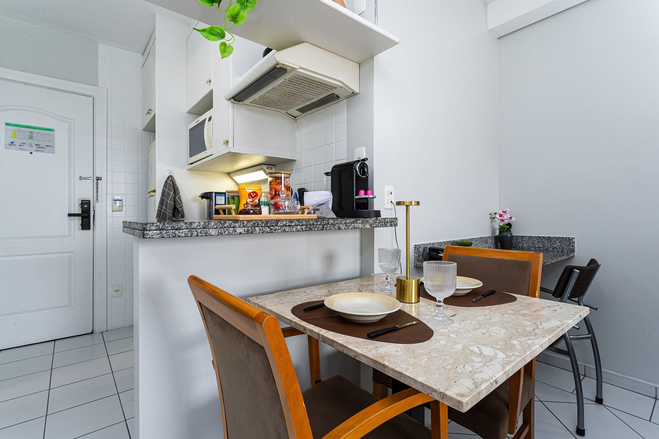 A compact kitchen with a dining area, white walls, and a tiled floor.