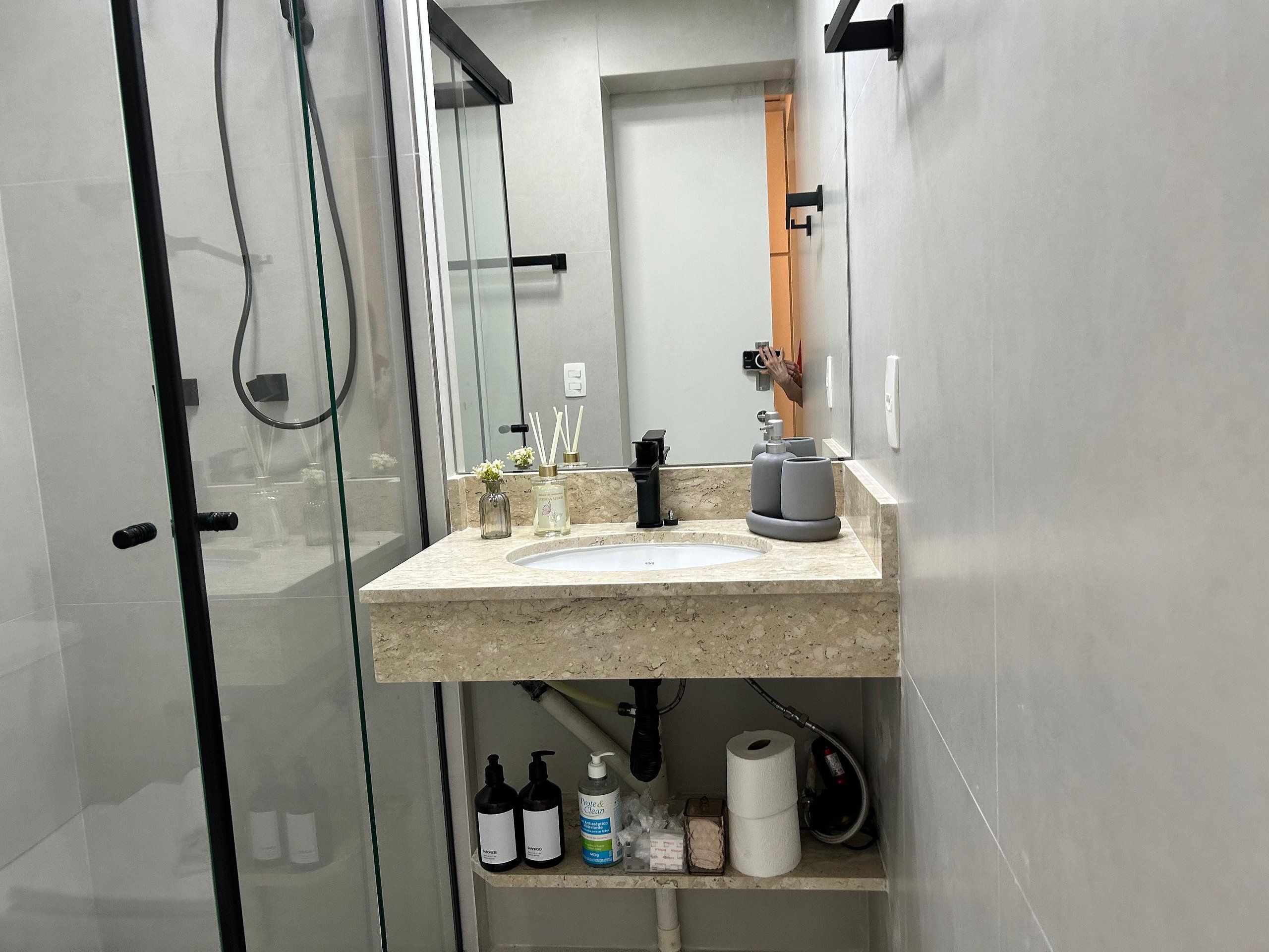 Un baño moderno con cabina de ducha de vidrio, lavamanos de mármol y espejo.