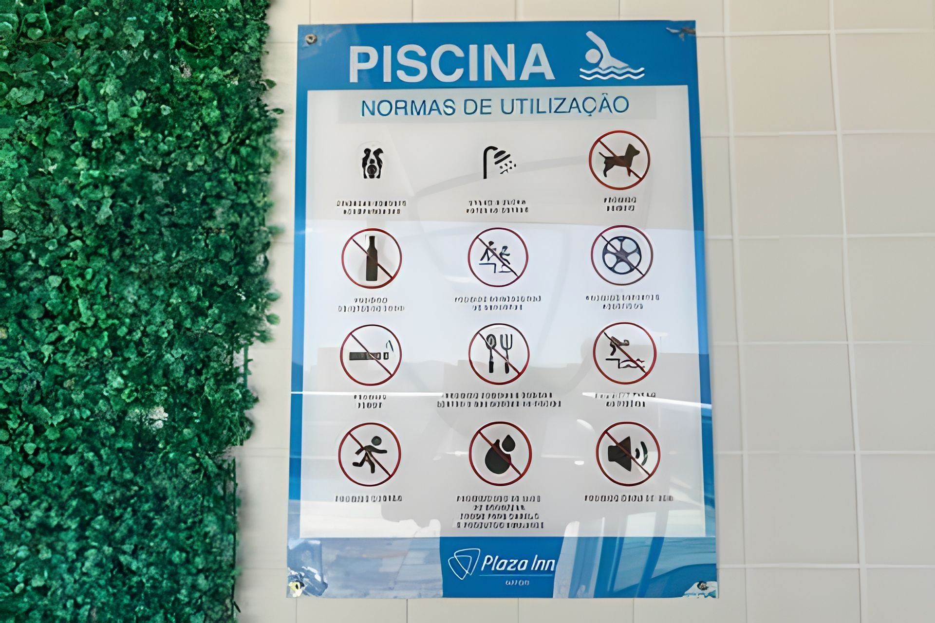 Um aviso com regras de utilização para uma piscina, incluindo proibição de mergulhos, bebidas alcoólicas, comida, nadar sozinho e música alta.