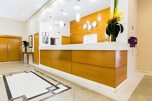 A reception area with a wooden reception desk, a white floor, and a reception counter. - Perdizes Residence Flat CondomÃnio (São Paulo)