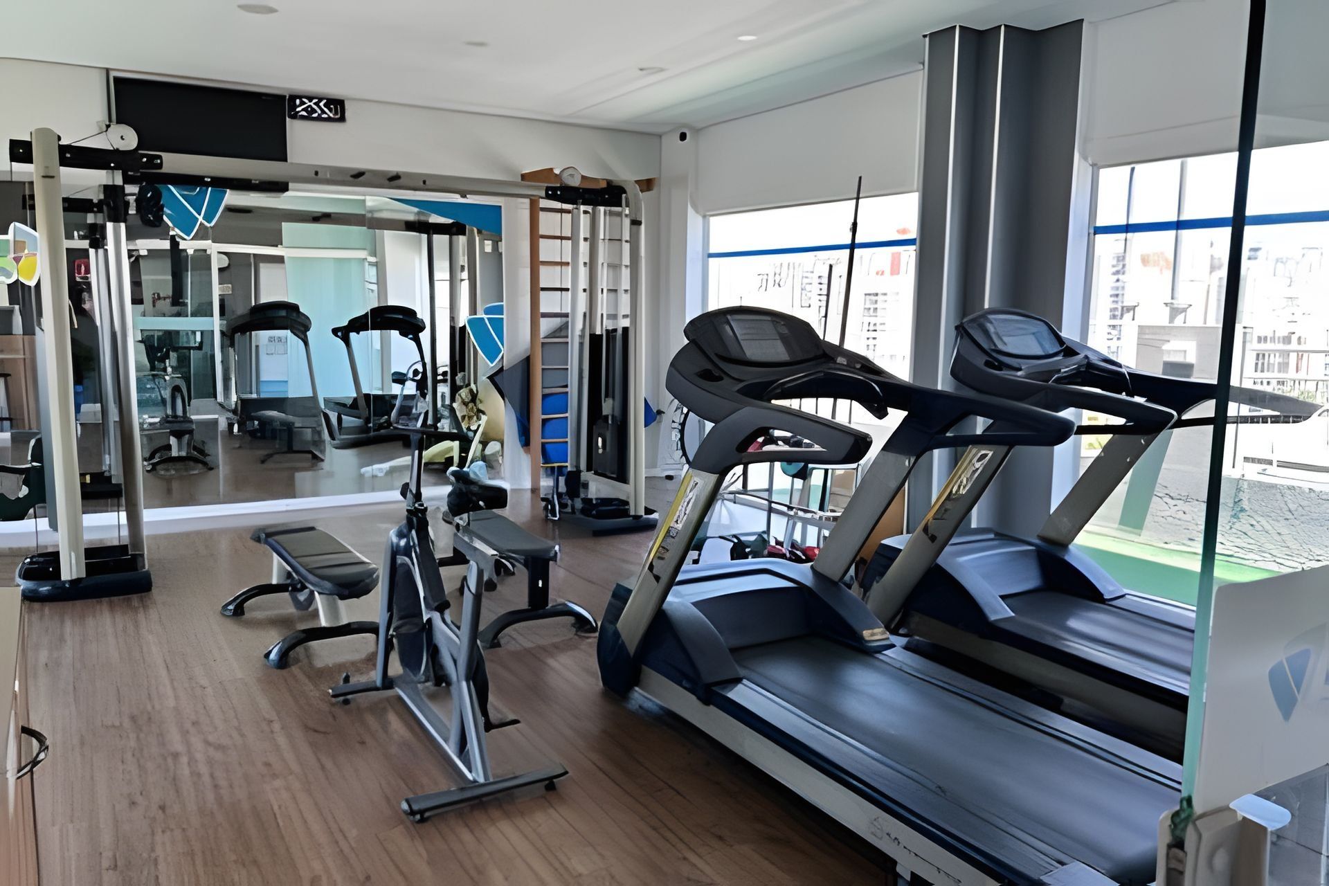Une salle de sport équipée de tapis de course, d’appareils d’exercice et dotée de grandes fenêtres.