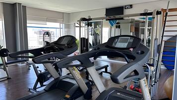 A gym with treadmills, weight machines, and a mirror wall.