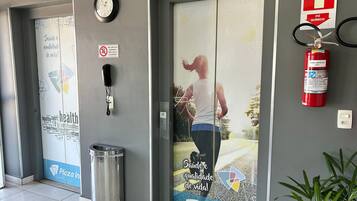 A hotel entrance with a sign for Plaza Inn, a fire extinguisher, a phone, and a trash bin.
