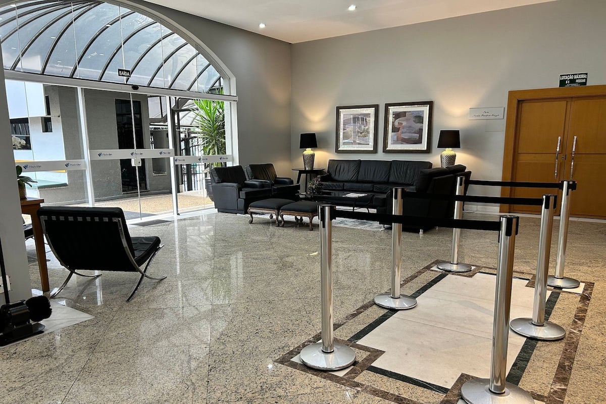 Un hall d’entrée avec un plafond en verre, un comptoir d’accueil, un canapé en cuir noir et un meuble en bois.