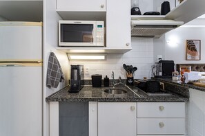 A compact kitchen with a microwave, coffee maker, sink, and a small countertop area. - Perdizes Residence Flat Condomínio  (São Paulo)