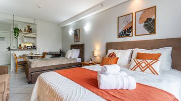 A hotel room with a bed, a desk, a chair, and a kitchenette.