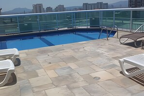 A rooftop pool with a glass balustrade, stone tiles, and white lounge chairs. - Perdizes Residence Flat CondomÃnio (São Paulo)