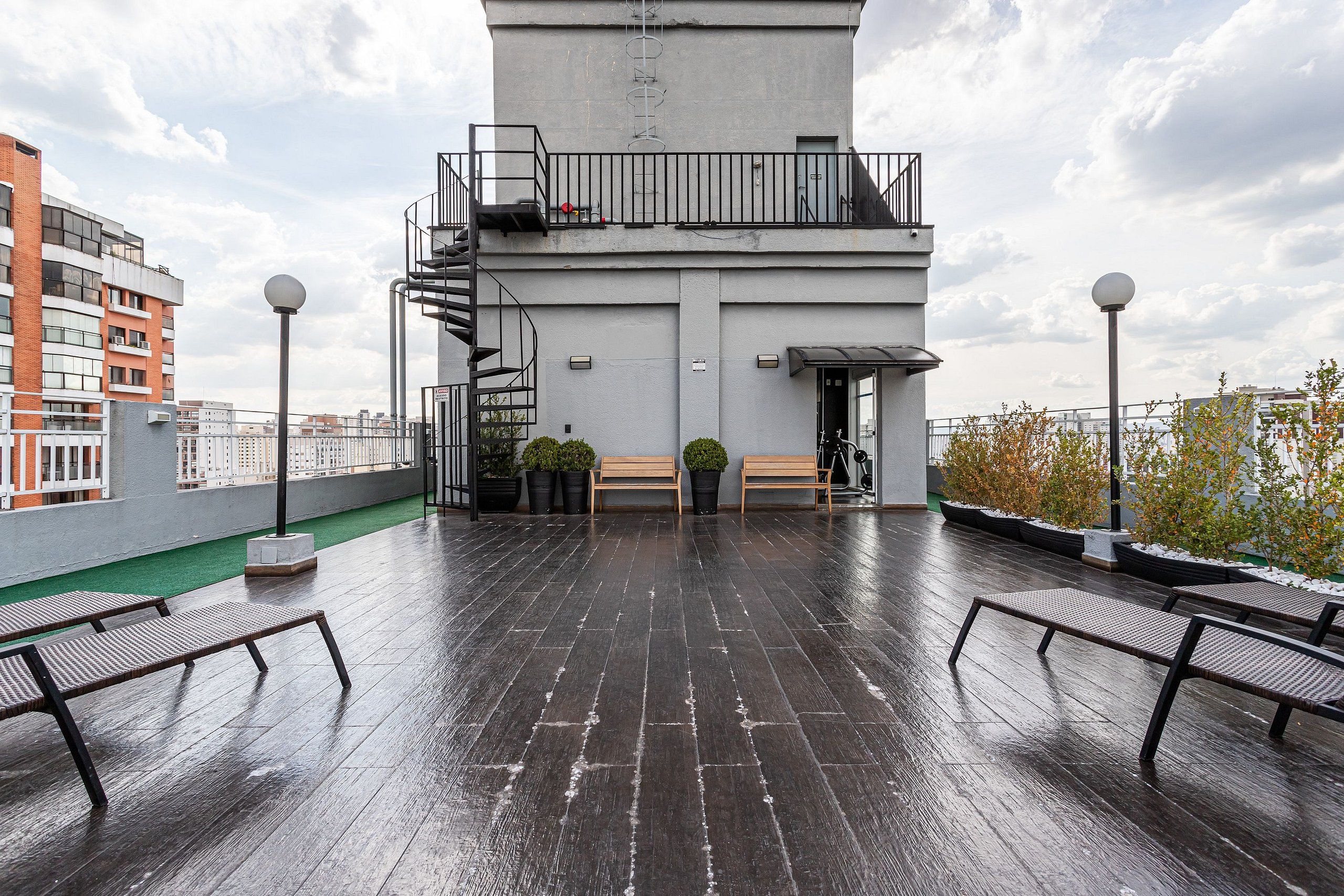 A rooftop terrace with a view of the city, a staircase, and a bench area.