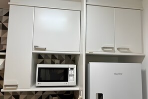 Una cocina con armarios blancos, un microondas y un refrigerador.