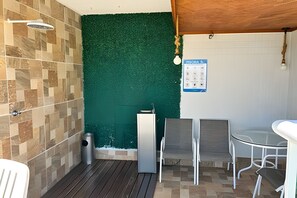 A bathroom with a green wall, a shower, a sink, and a small table with chairs. - Perdizes Residence Flat CondomĂnio (SĂŁo Paulo)
