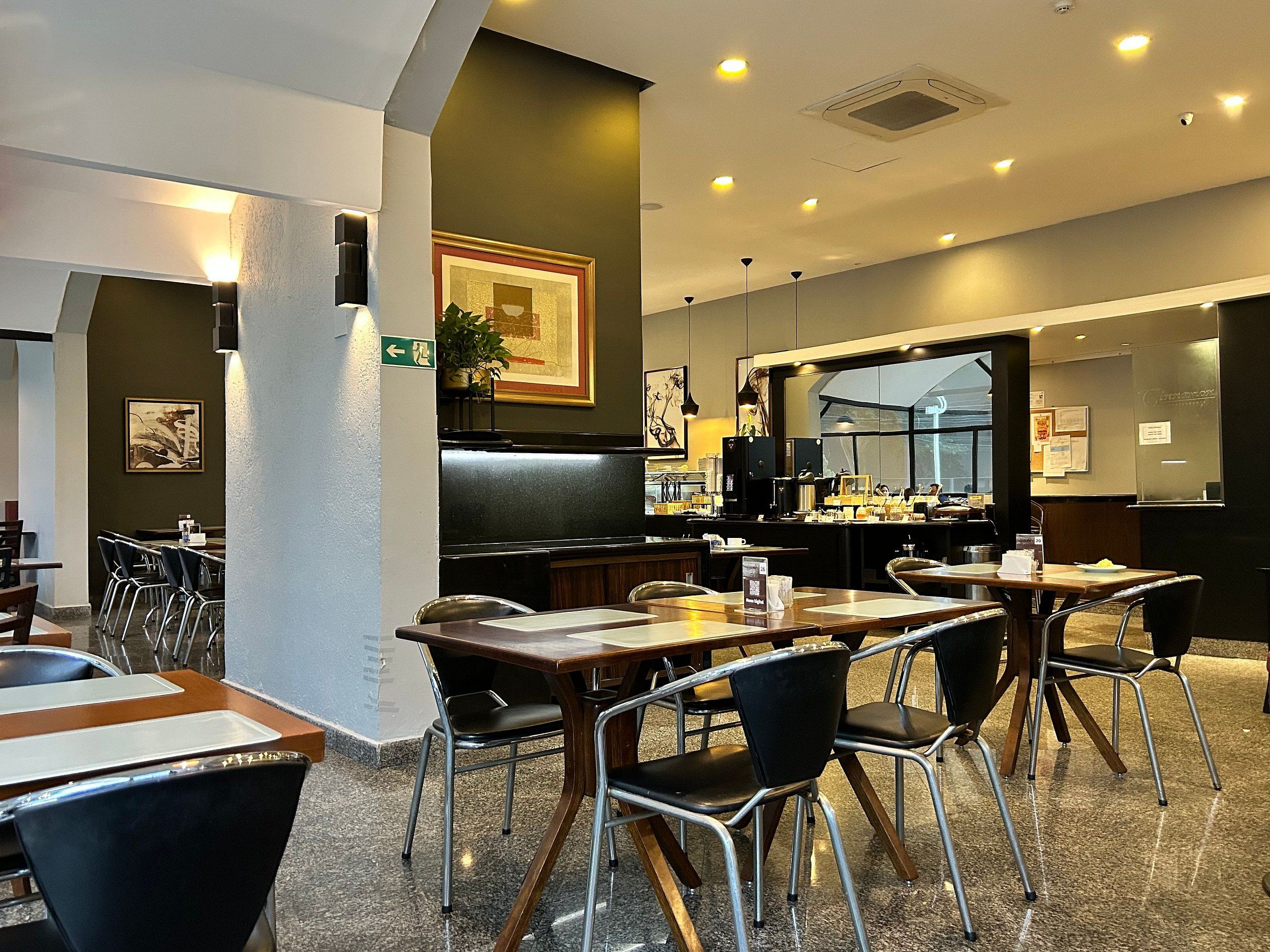 A restaurant interior with tables, chairs, a counter, and a large window.