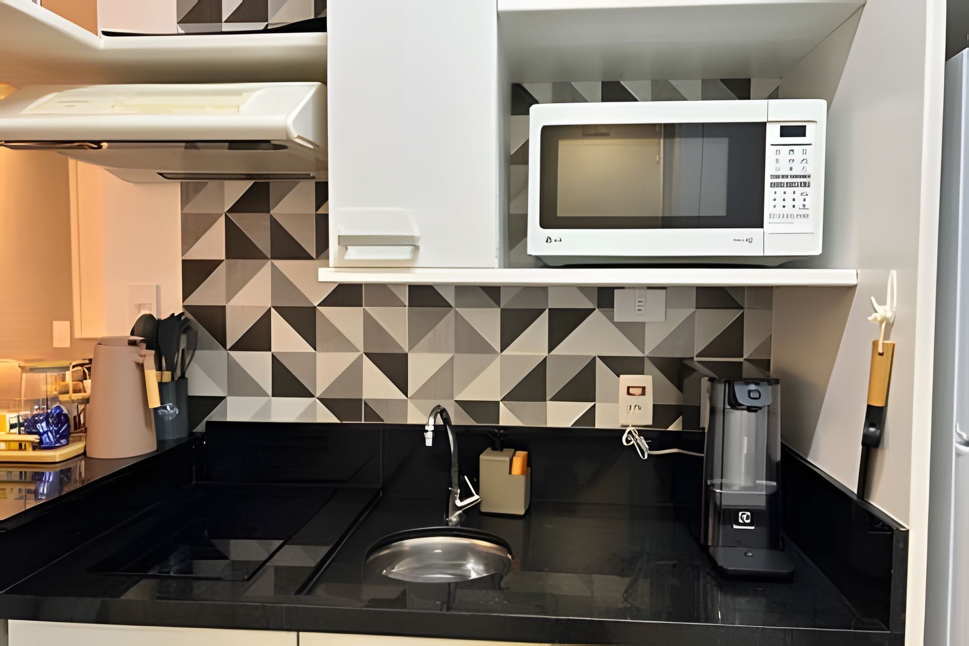 A kitchen with a microwave, sink, and coffee maker.