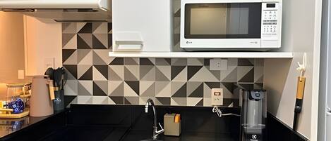 A kitchen with a microwave, sink, and coffee maker.