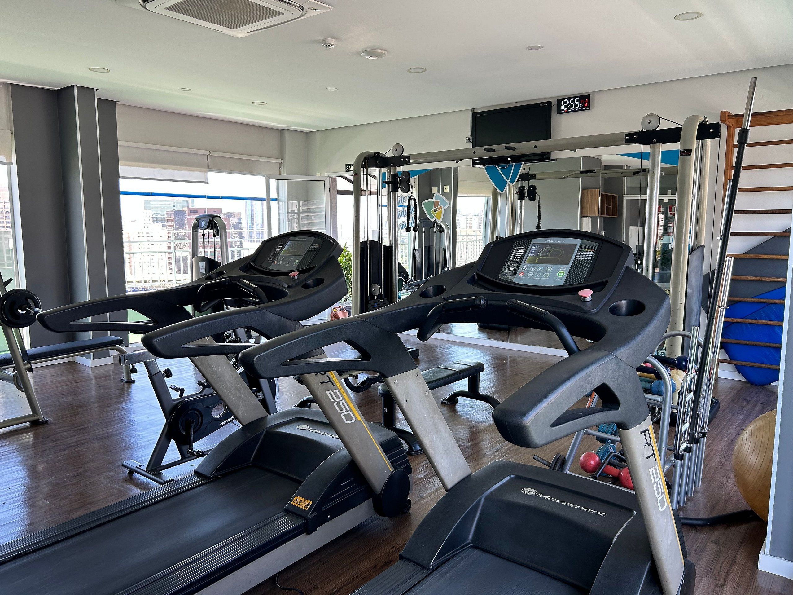 A gym with treadmills, weight machines, and a large window.